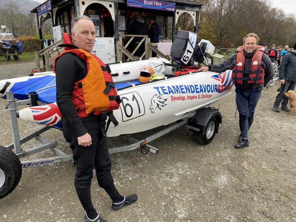 Men in life vests beside canoe on trailer.