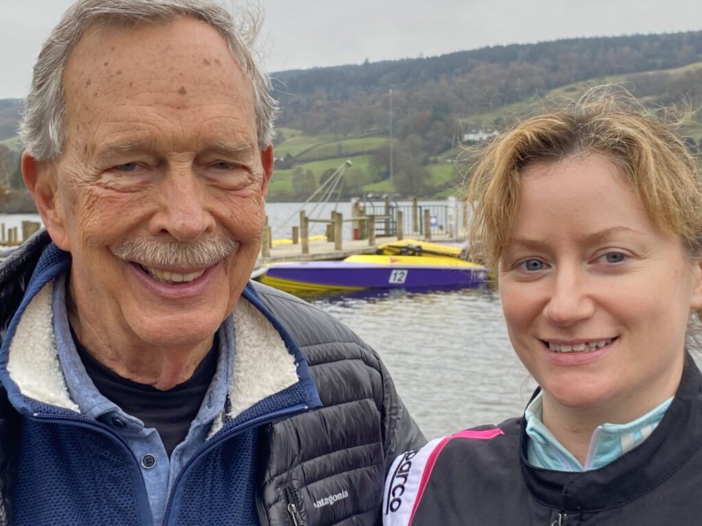Two smiling people by a lakeside