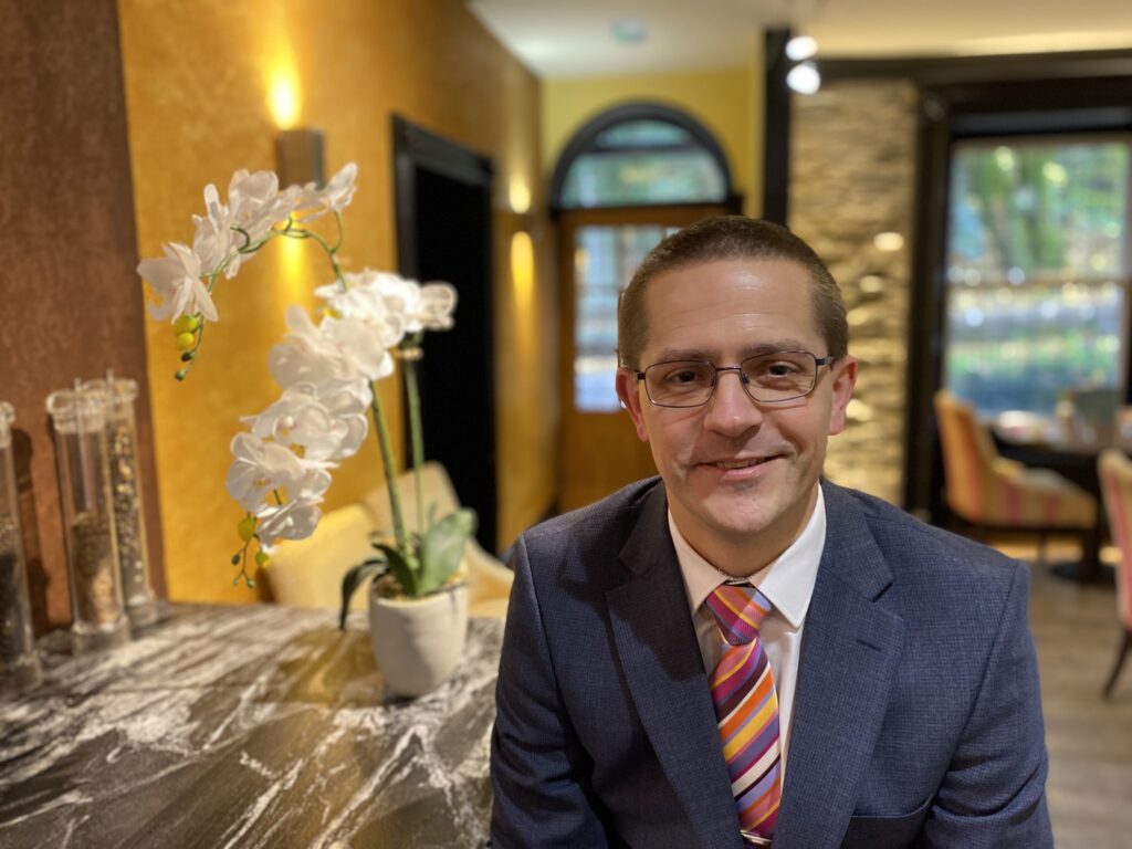 Man in suit with colourful tie, indoor setting.