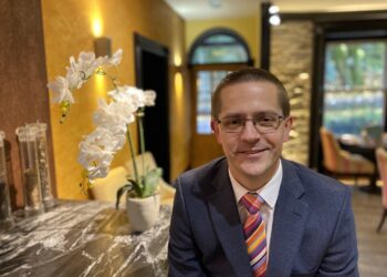 Man in suit with colourful tie, indoor setting.