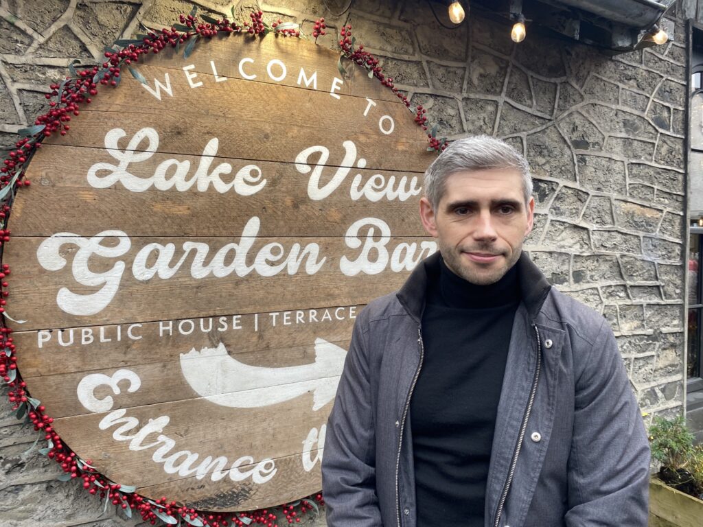 Person near Lake View Garden Bar sign outside.