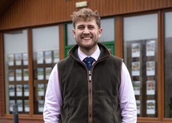 Smiling person in formal wear outside office building.