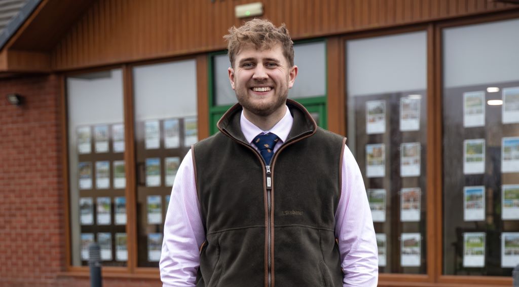 Smiling person in formal wear outside office building.