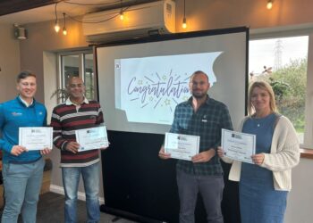 Four people holding certificates at congratulations event.