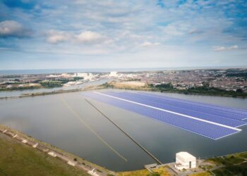 Floating solar panels on reservoir near industrial area.